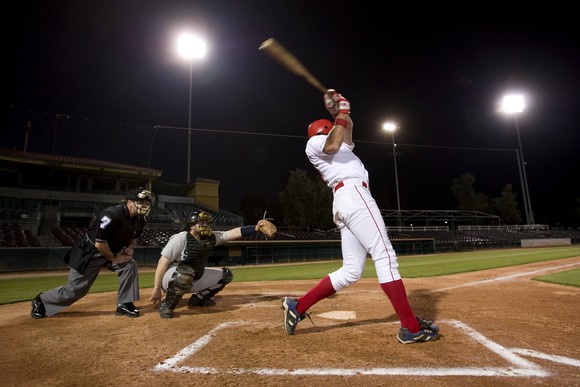 Baseball batter, catcher, and umpire during a night game. 