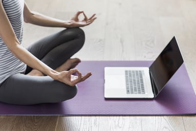 A woman doing yoga with a laptop
