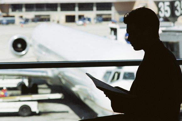 A man is silhouetted in front of an airplane parked on the tarmac.