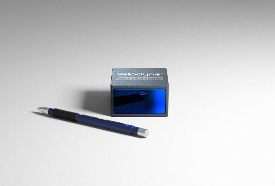A Velabit, a small black and blue box, shown with a mechanical pencil for scale 