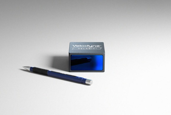 A Velabit, a small black and blue box, shown with a mechanical pencil for scale 