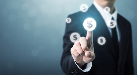 Businessman in a suit touching a floating dollar sign image with his finger.