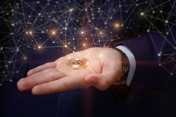 Hand holding a gold token with bitcoin symbol.