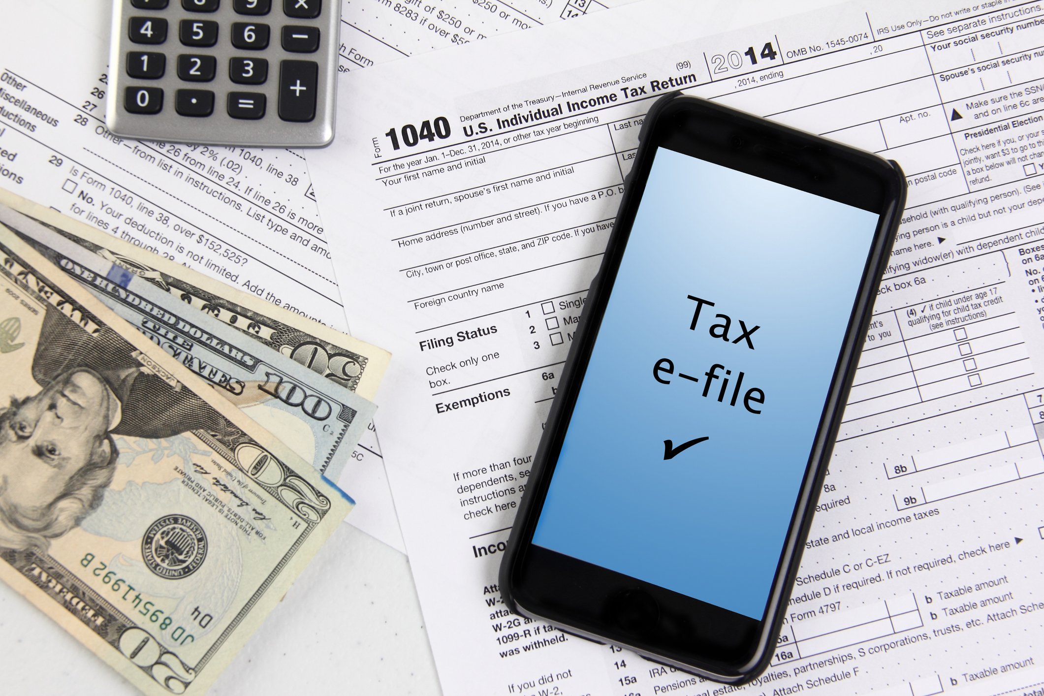 Tax forms, cash, calculator, and smartphone