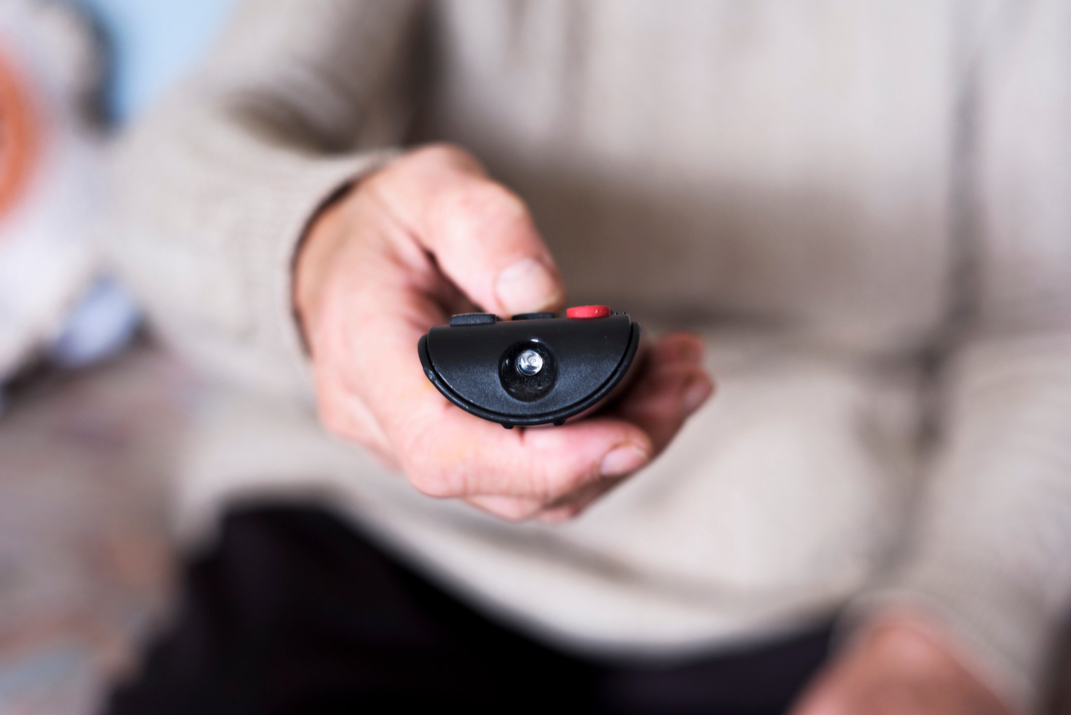 A closeup on a hand operating a remote control. 