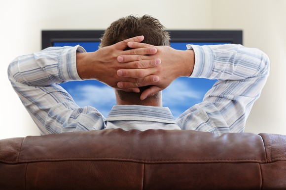 A man watches a big-screen TV from his couch.