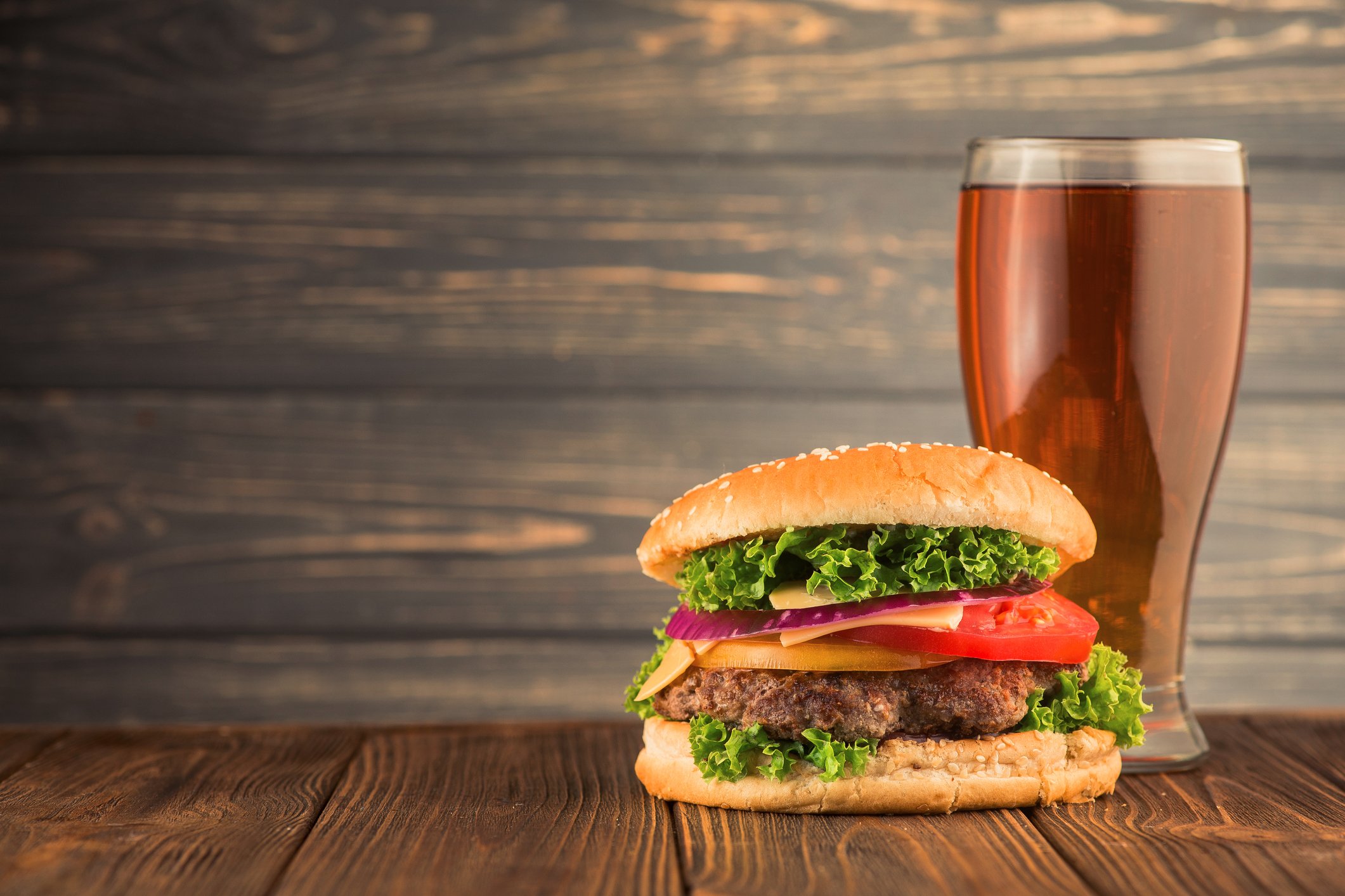 A large burger with a glass of beer.