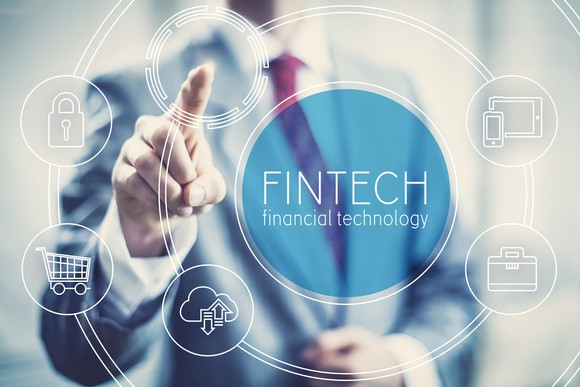 A business man points at a series of digital icons representing fintech.