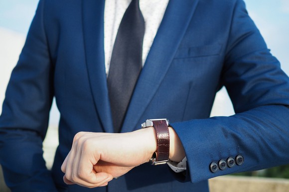 Man in suit checks his watch.