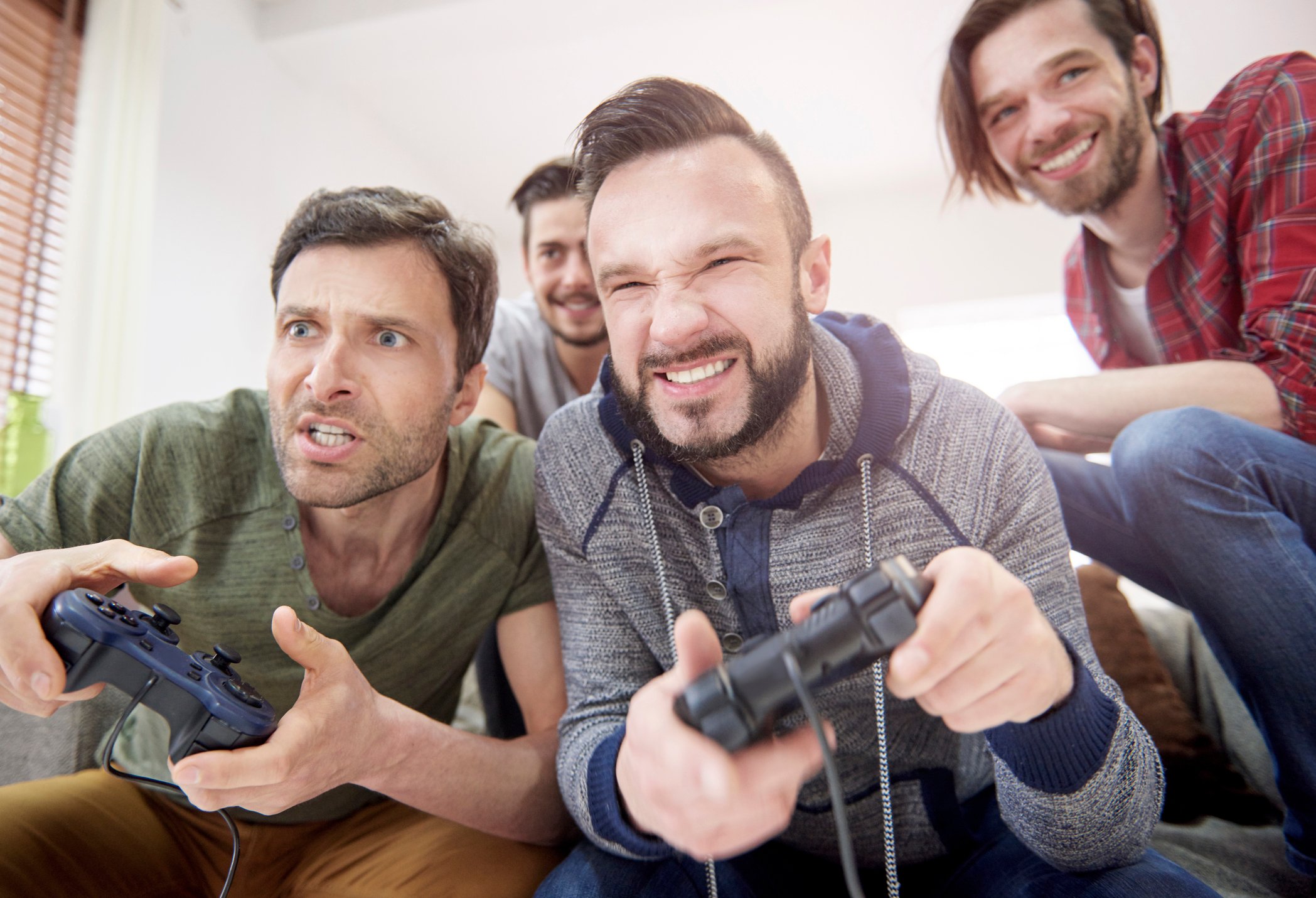 Men holding controllers play a video game together.