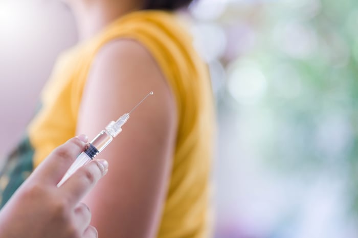 Hand holding a syringe in front of a shoulder