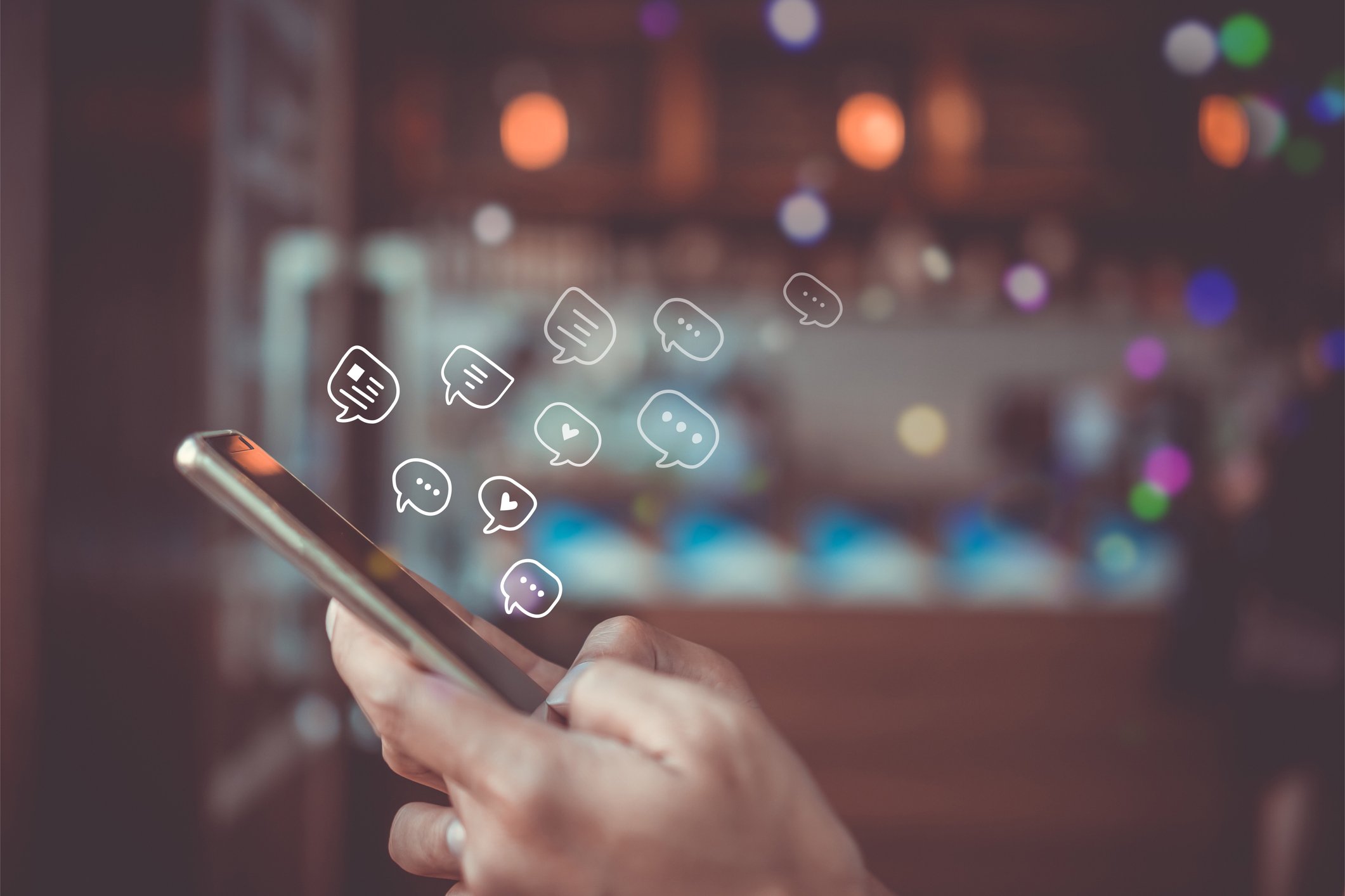 Person holding a phone with cartoon dialog bubbles floating above it