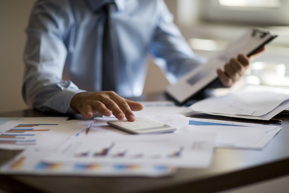 Man in suit using calculator at desk with financial papers