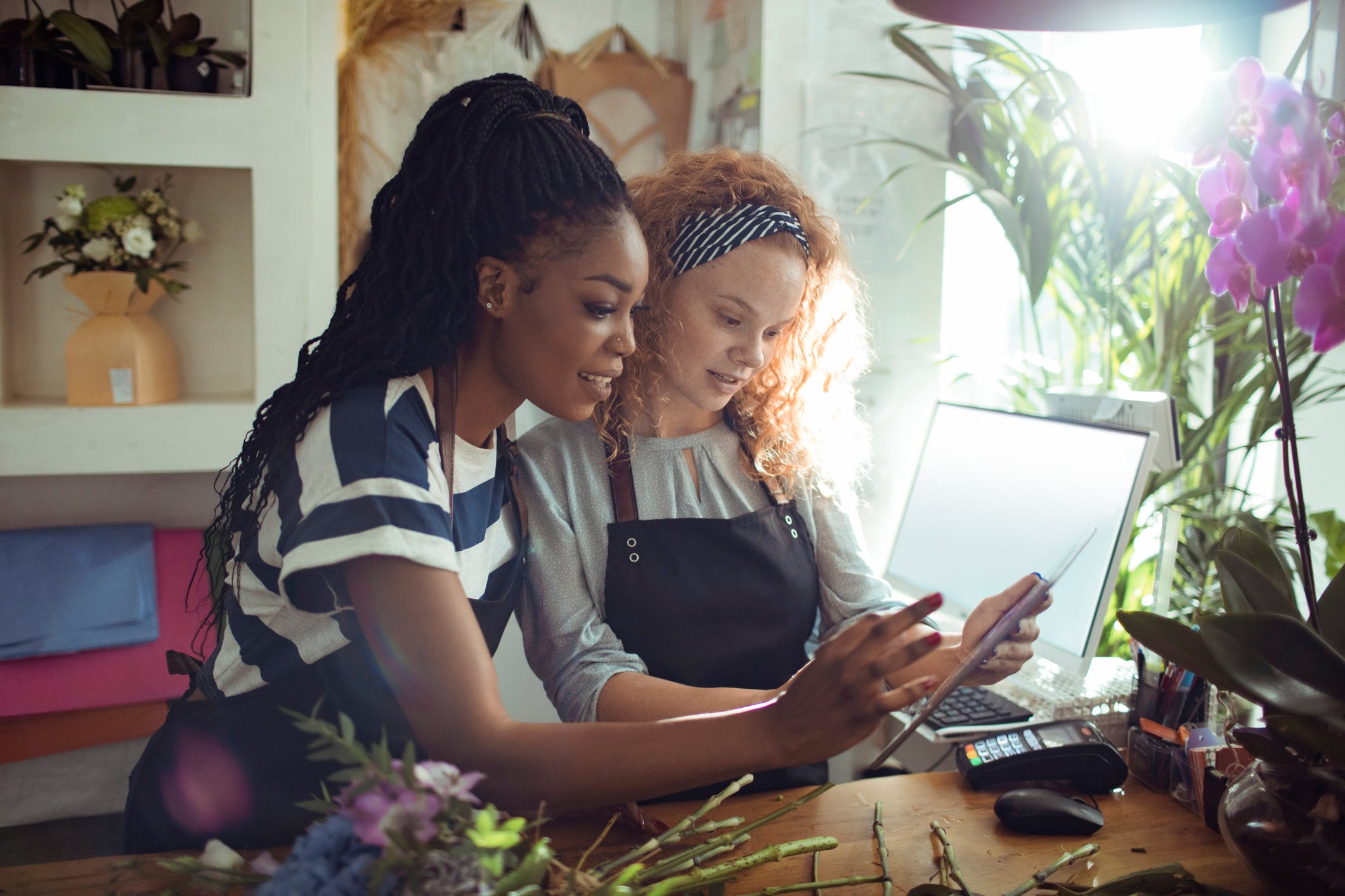 Two women looking at tablet behind store counter