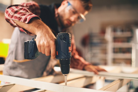 A man uses a drill during a home improvement project.