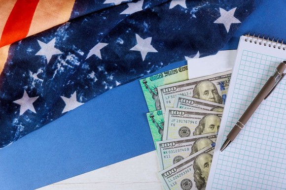 Money, checks, and a notepad atop an American flag.