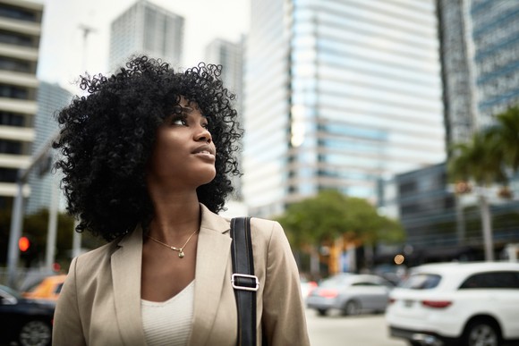 Person looking up, with street traffic and buildings behind.