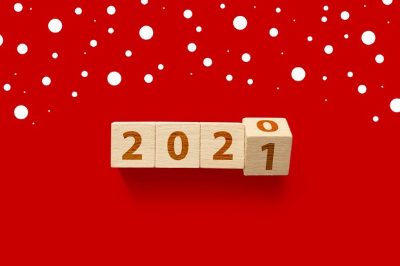 Wooden blocks changing from 2020 to 2021 on a red background with white polka dots.