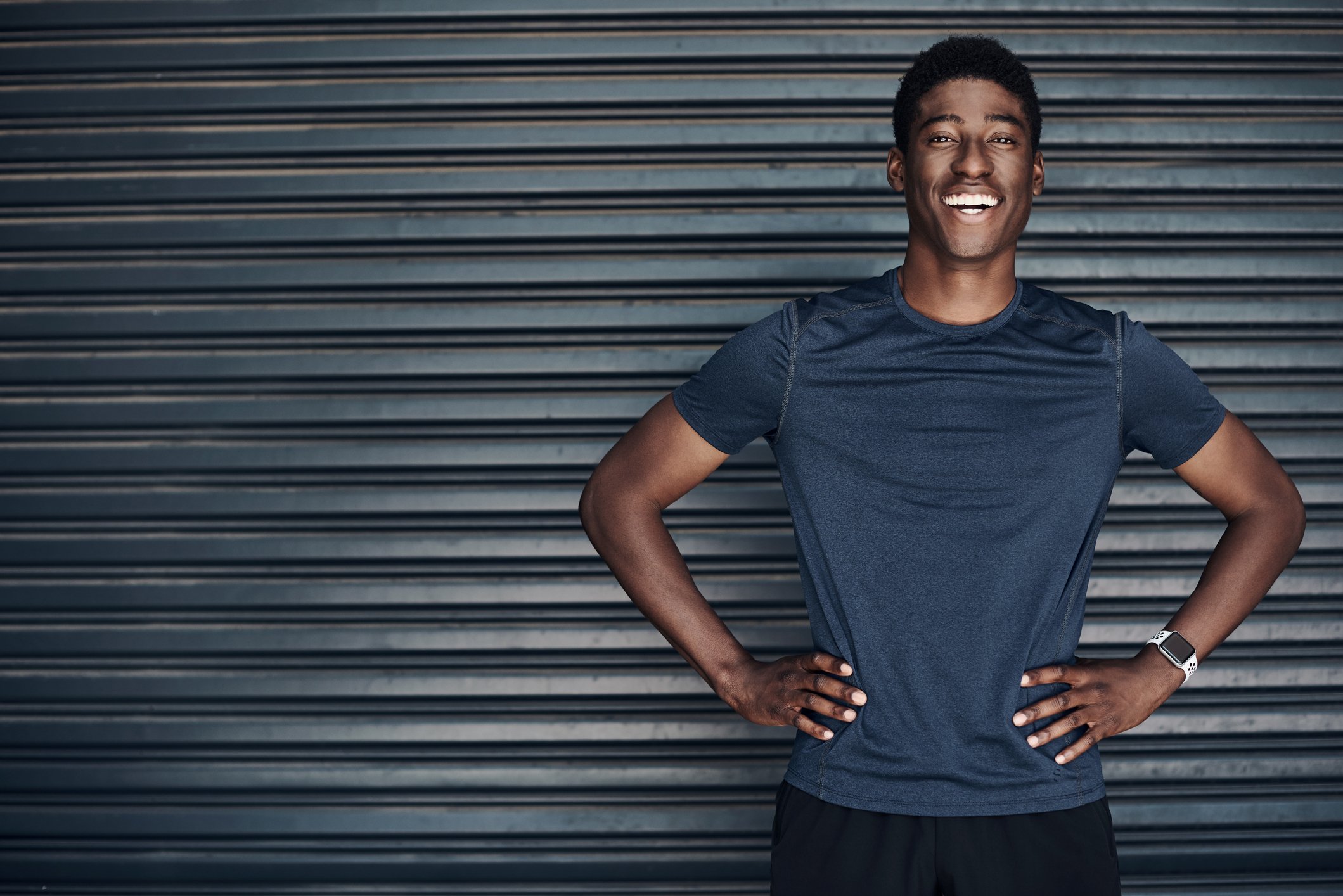 A man smiling with his hands at his hips.