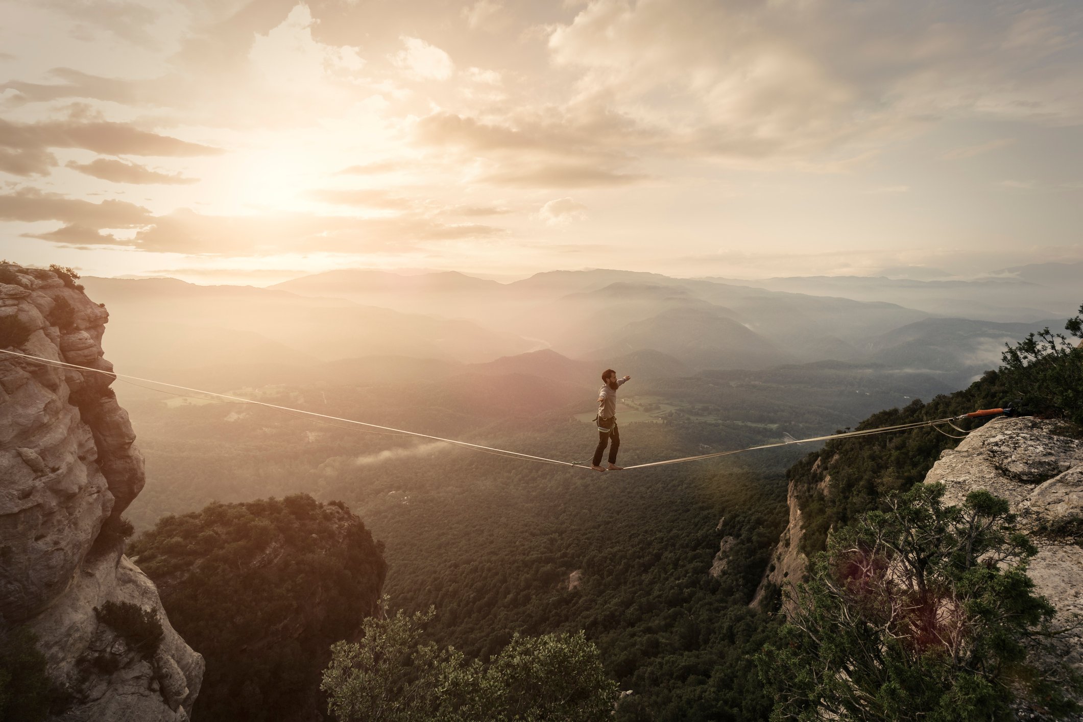 An individual walking a tightrope with mountains in the background