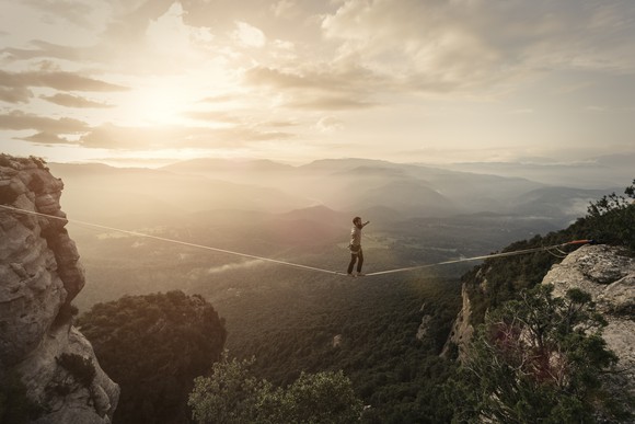 An individual walking a tightrope with mountains in the background