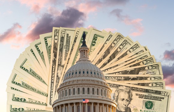 The United States Capitol building sits in front of a backdrop of $20 bills.