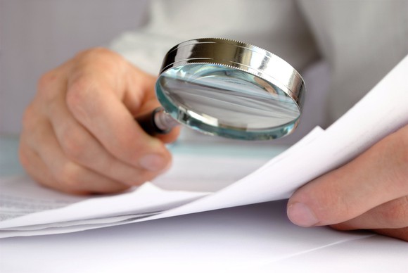 A magnifying glass being utilized to inspect some paperwork.