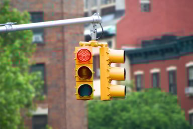 In front of buildings, a traffic light shows red 