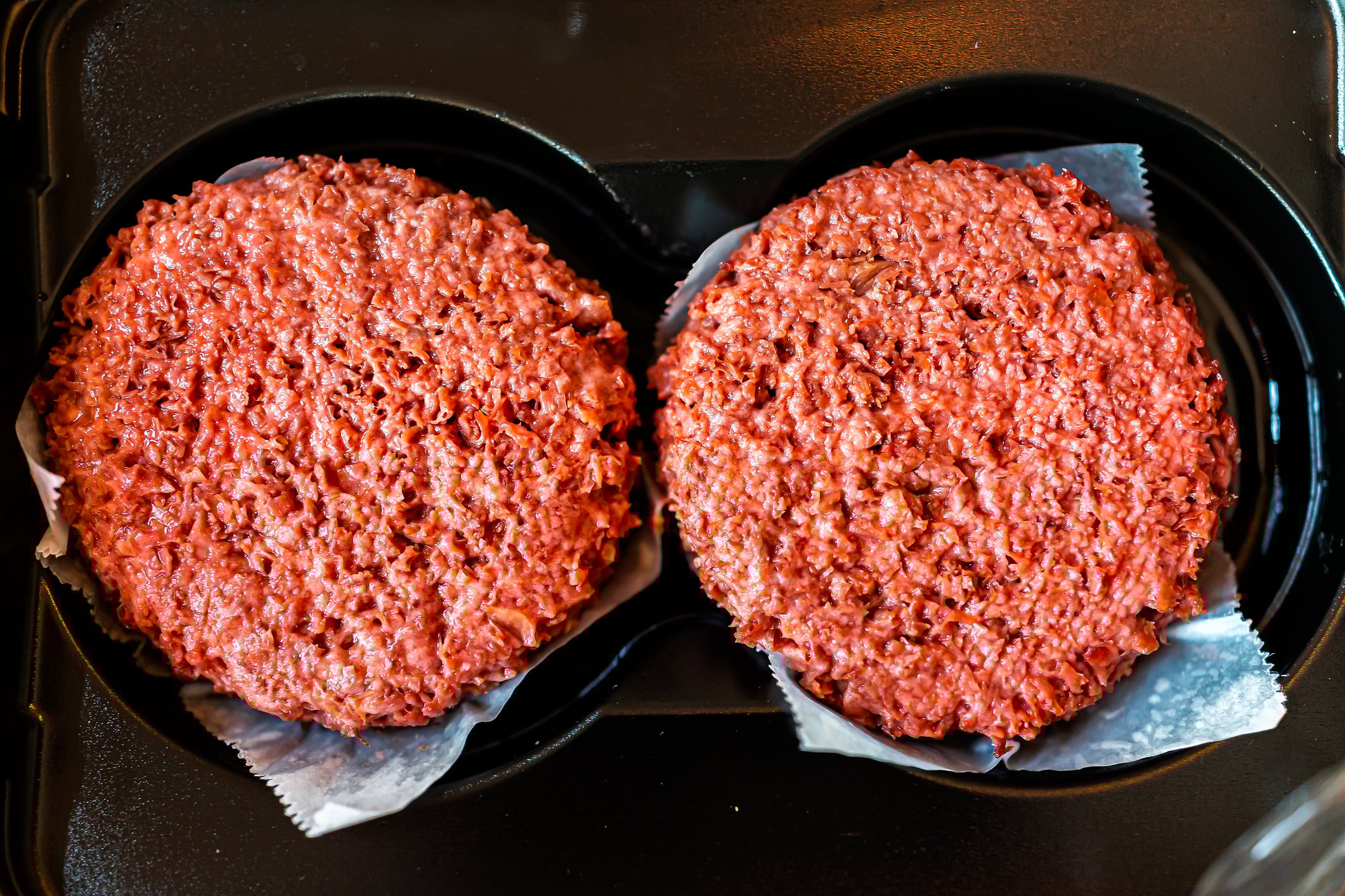 Two plant-based burger patties sitting side by side