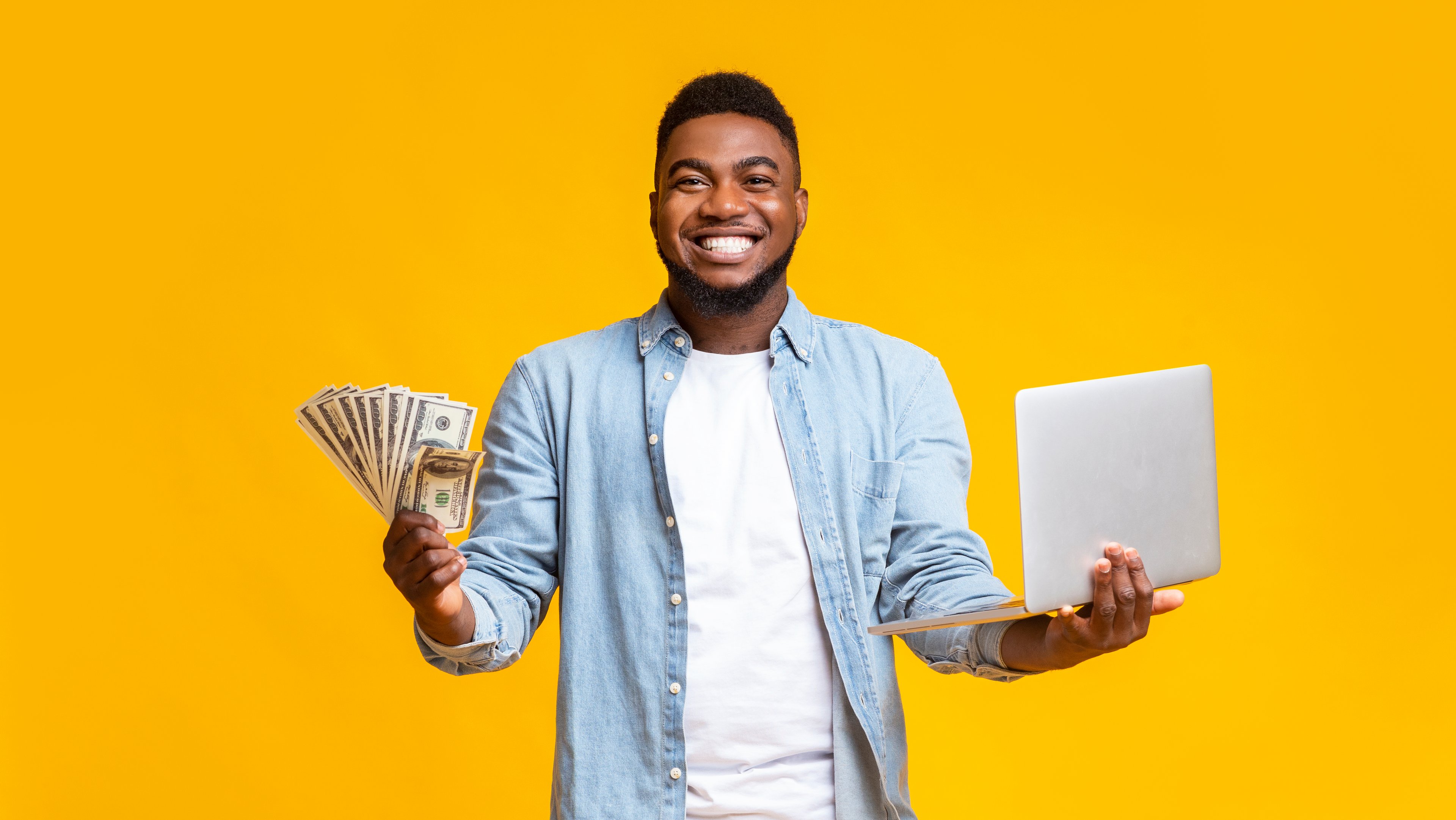 Man holding cash and laptop. 