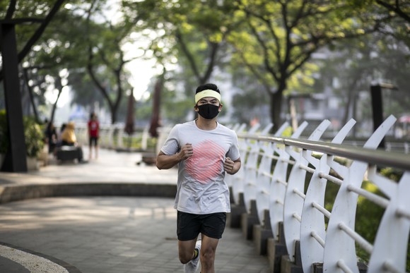 Man in face mask running along a bridge.