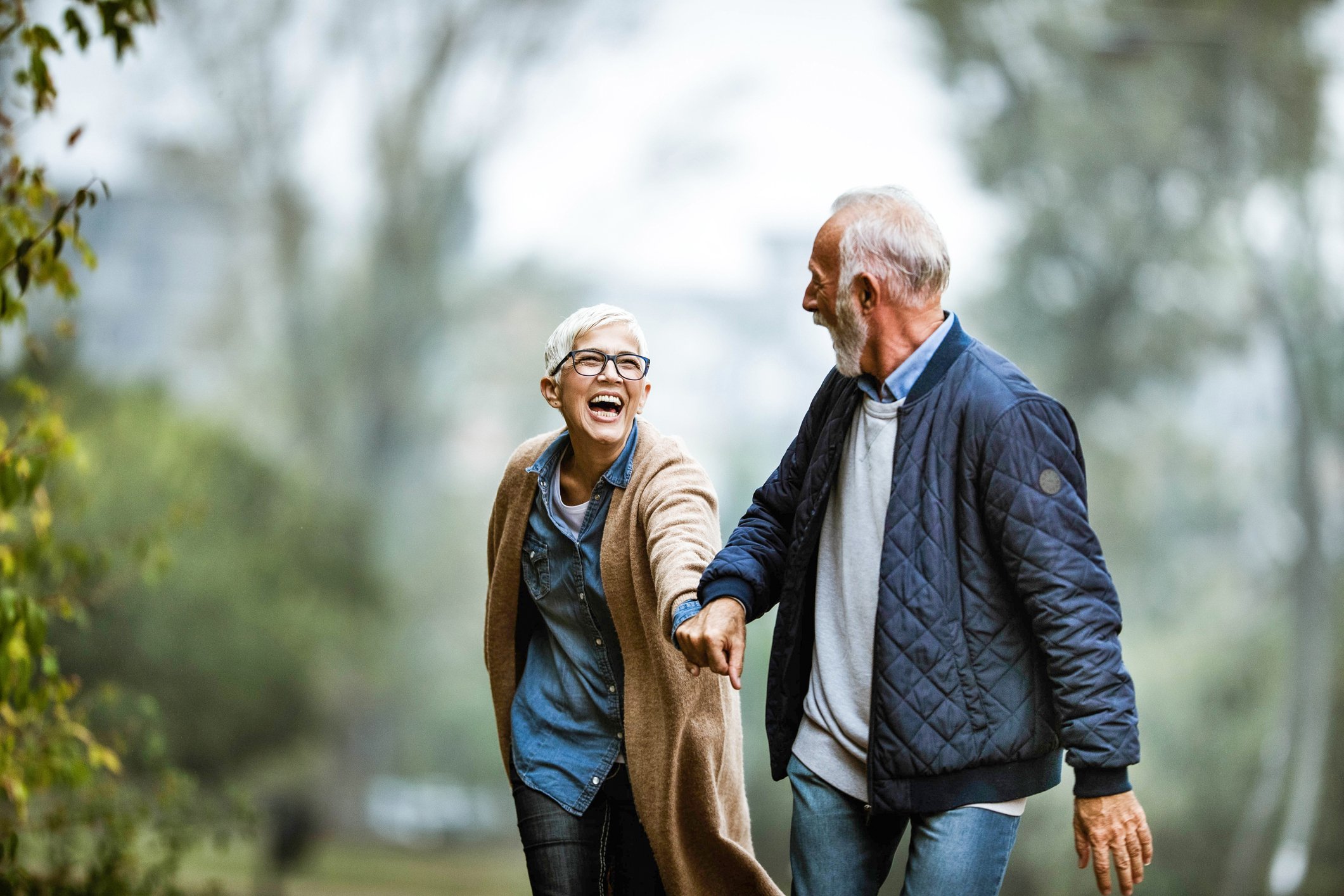 Smiling retiree couple holding hands and walking outside