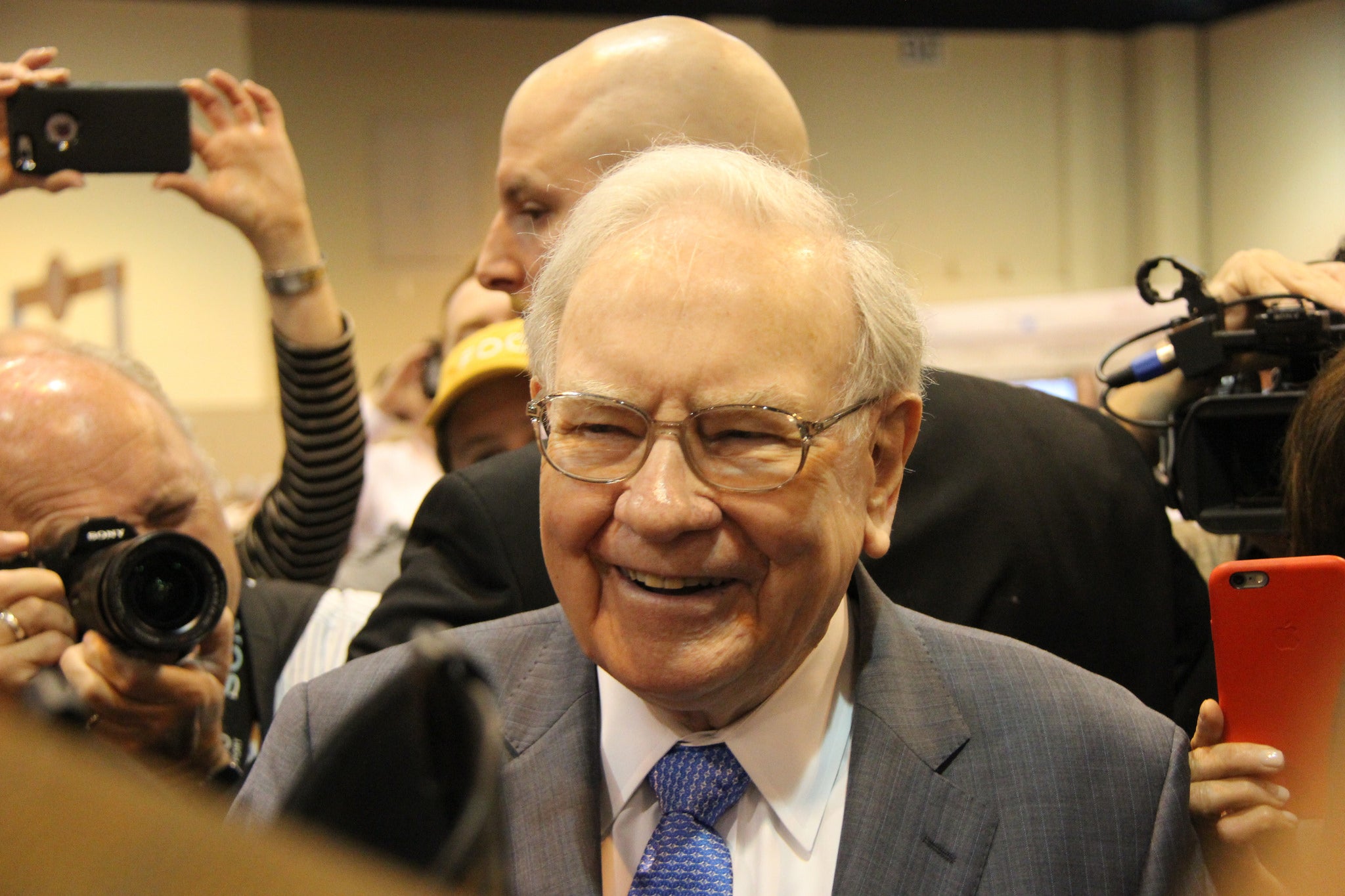 Smiling Warren Buffett with people in background