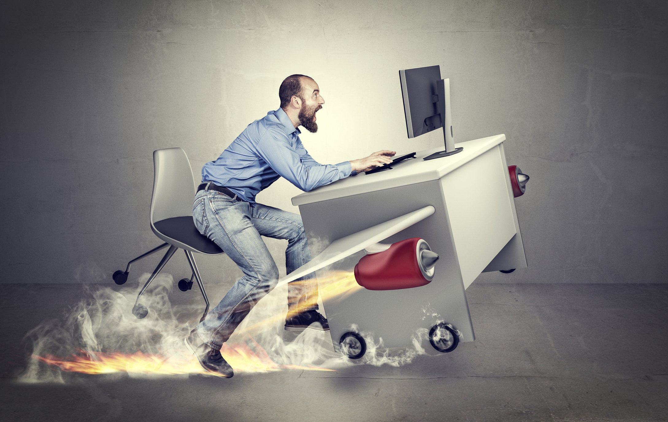 An office worker holds on to his desk as it takes off on a rocket-powered flight.