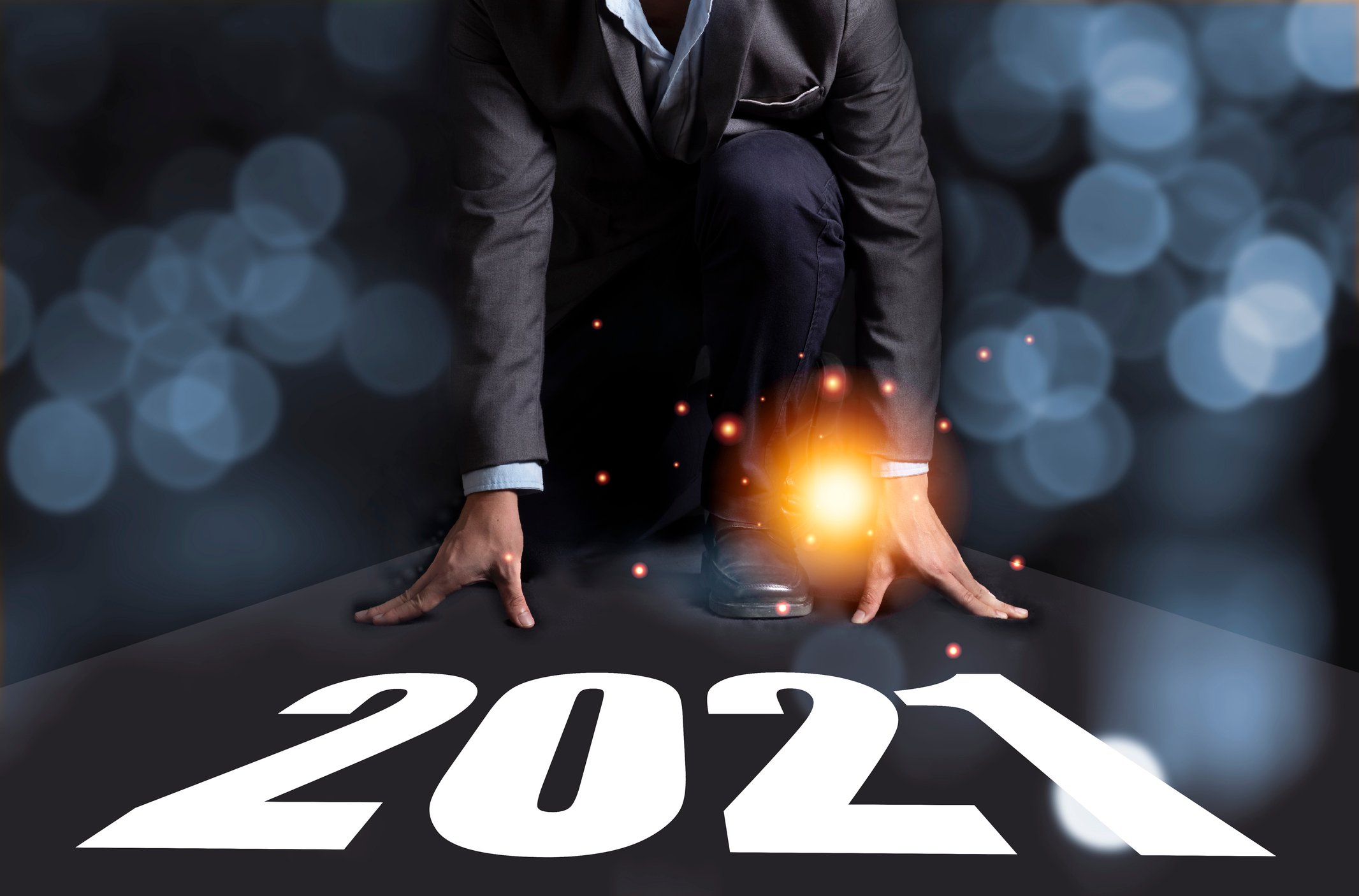An investor kneels as if to run a race with the year "2021" written at his feet.