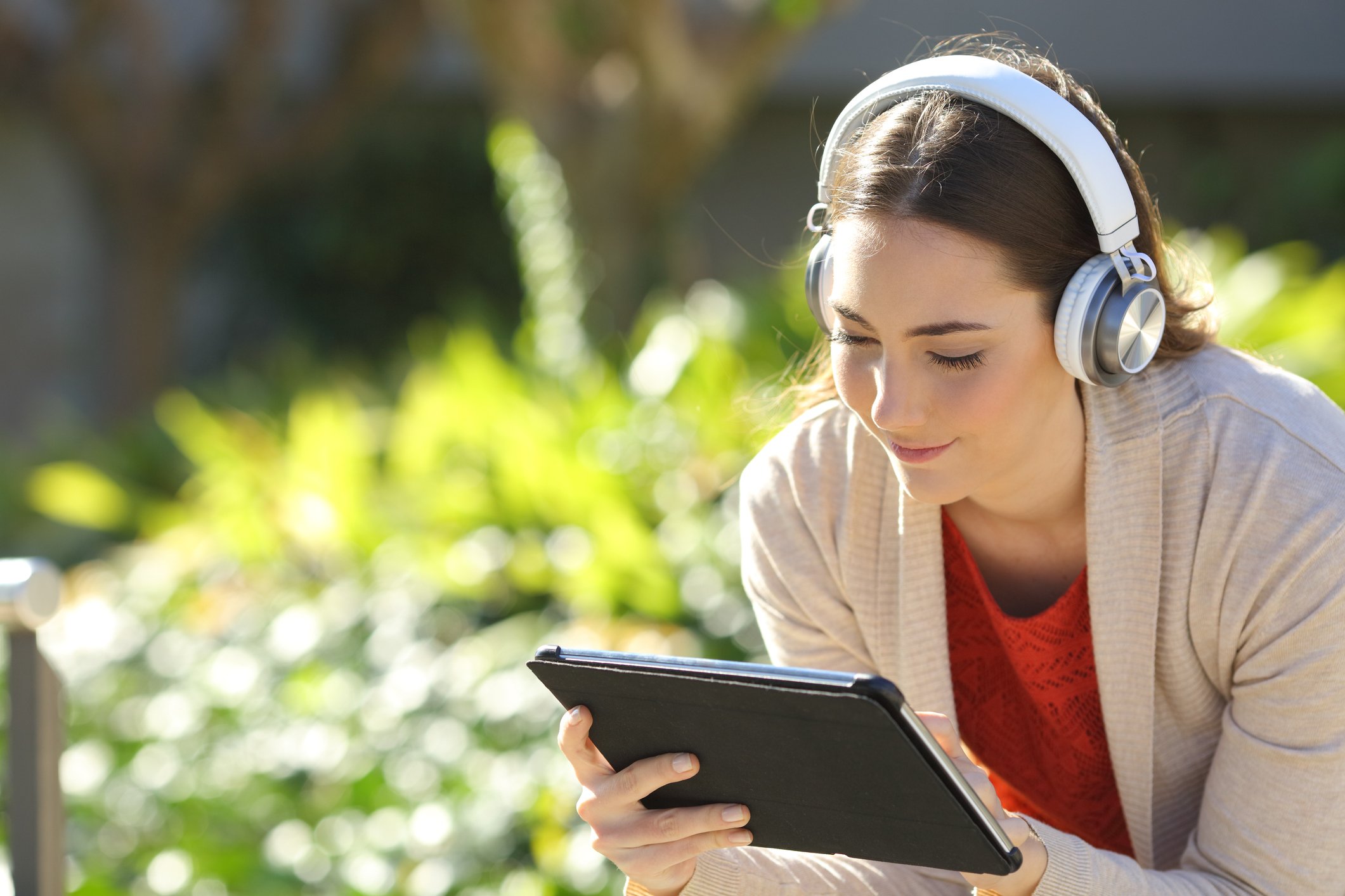Woman holding a tablet and wearing headphones.