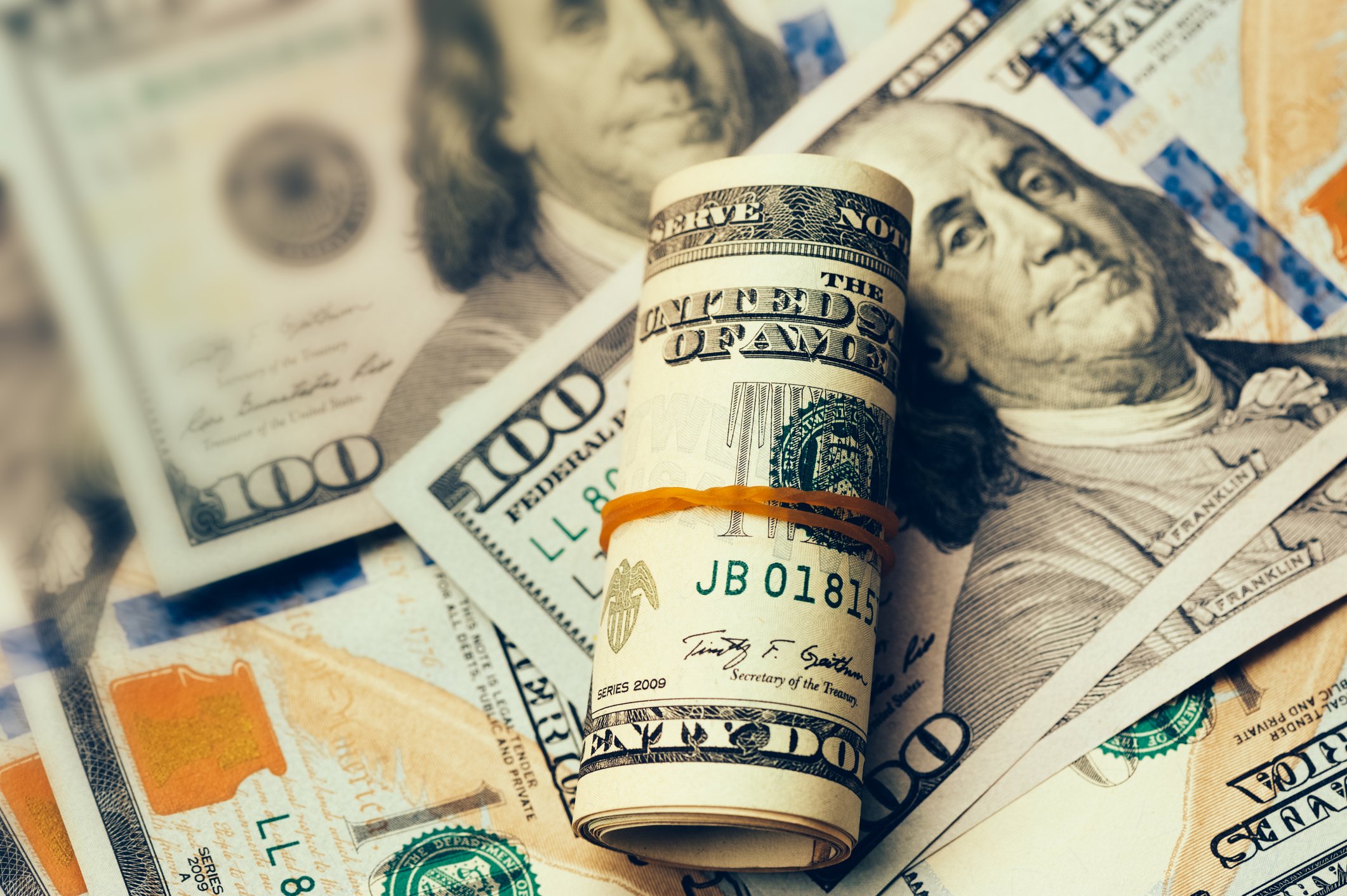 A roll of cash on top of $100 bills.