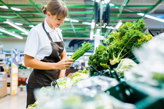 An employee restocking fresh produce.