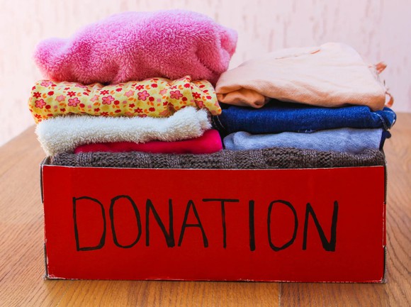 Box labeled donation with clothing piled in it.