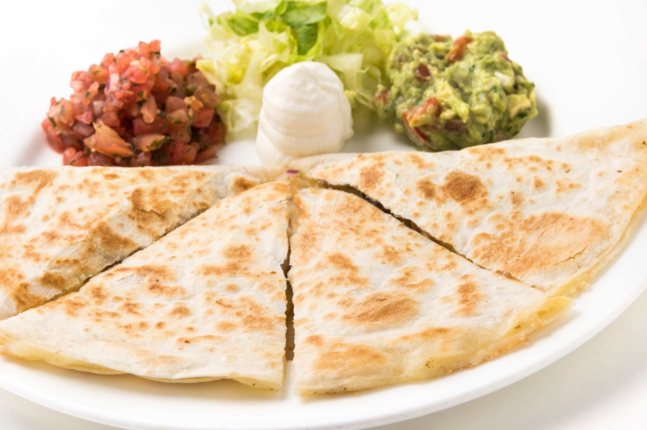 A plate with a quesadilla, salsa, sour cream, and guacamole. 