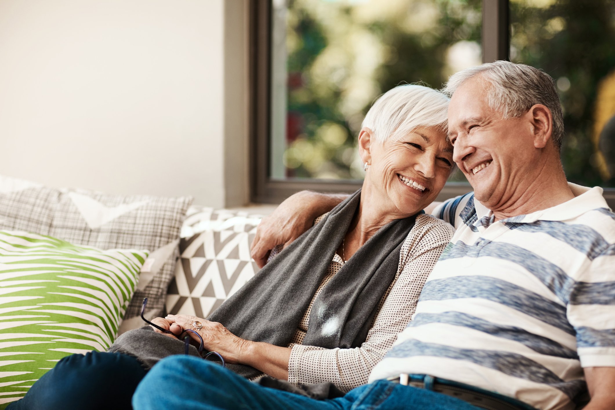 Senior couple sitting on the couch together smiling