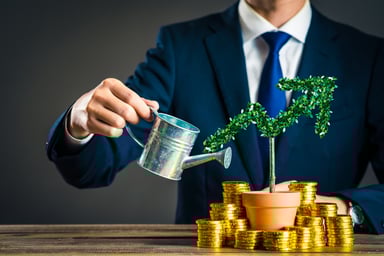 Businessman watering plant surrounded by coins