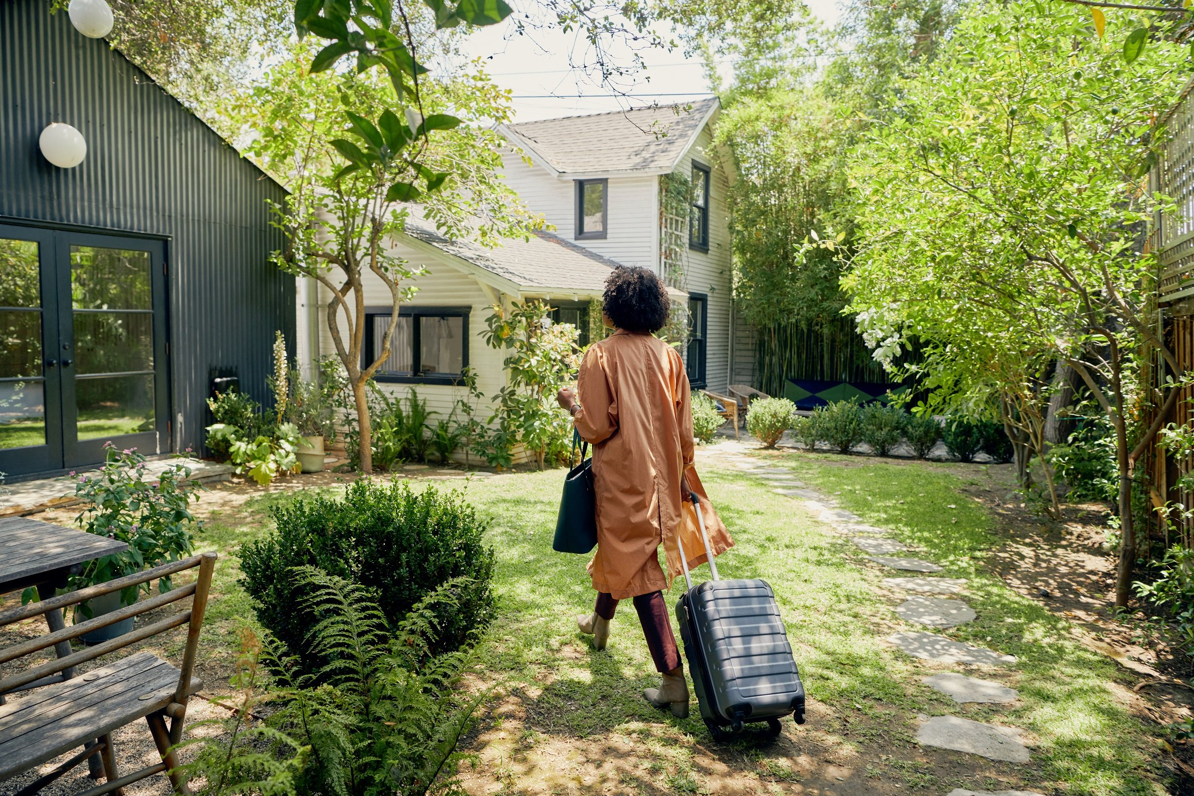 A woman with a suitcase walking to an Airbnb residence.