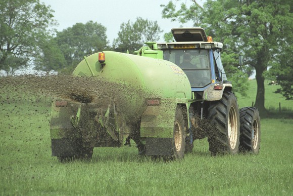 tractor spreading fertilizer in a grass field
