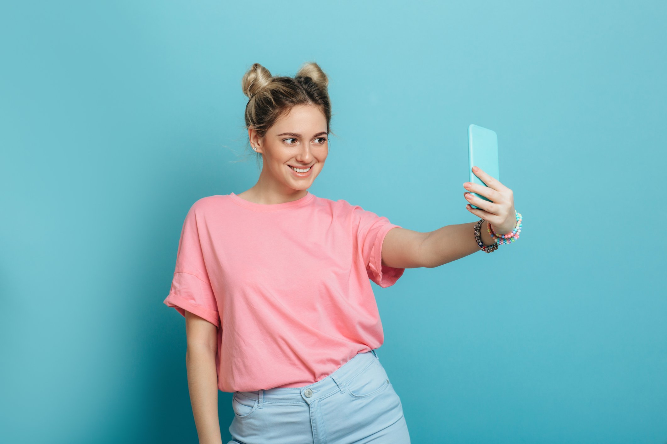 A young woman takes a selfie with her phone.