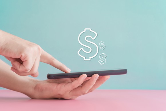 A person using a mobile phone displaying dollar signs.