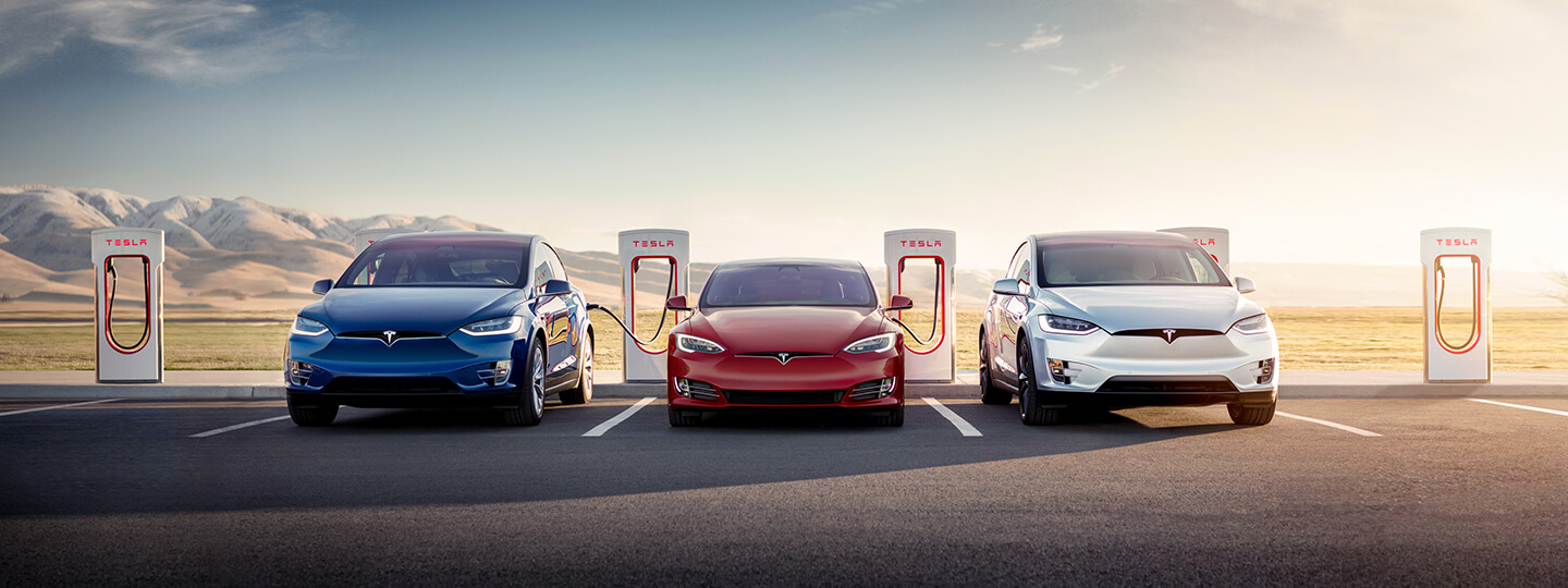 A lineup of three Tesla vehicles at a charge station.