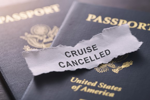 The words cruise canceled are typed on a torn piece of paper, which is on top of two passports. 