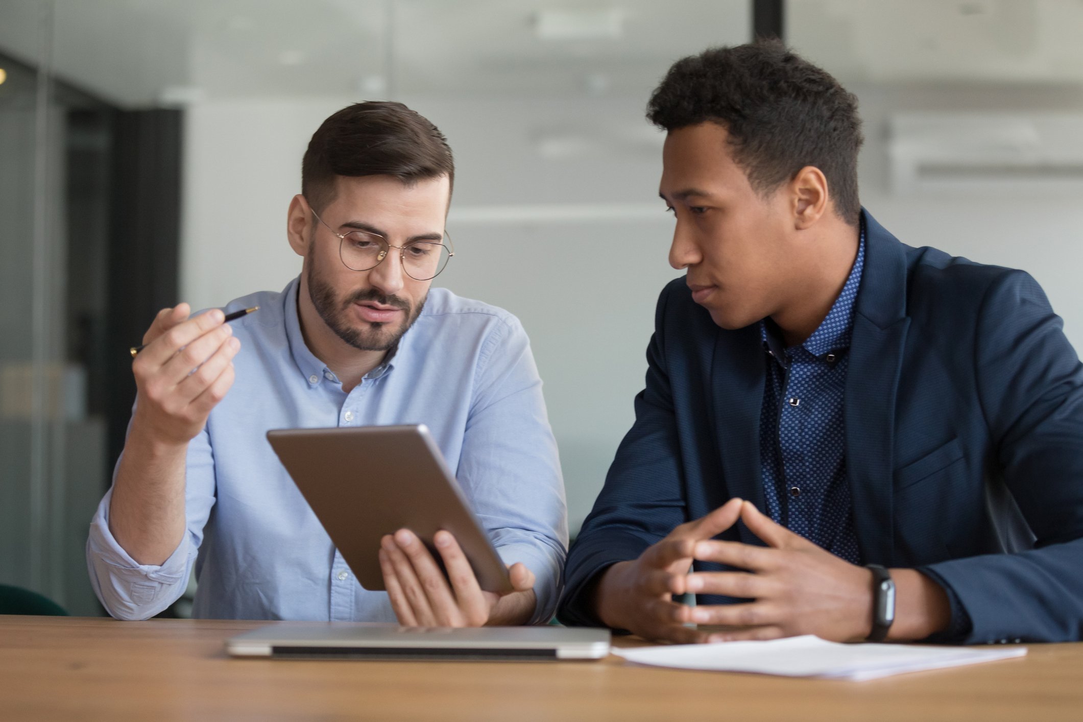 Two men looking at a tablet computer held by one of them.