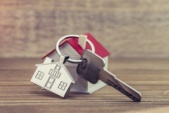 House key and key chain on wooden table.